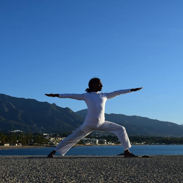 Person doing a powerful warrior yoga pose at sunrise.